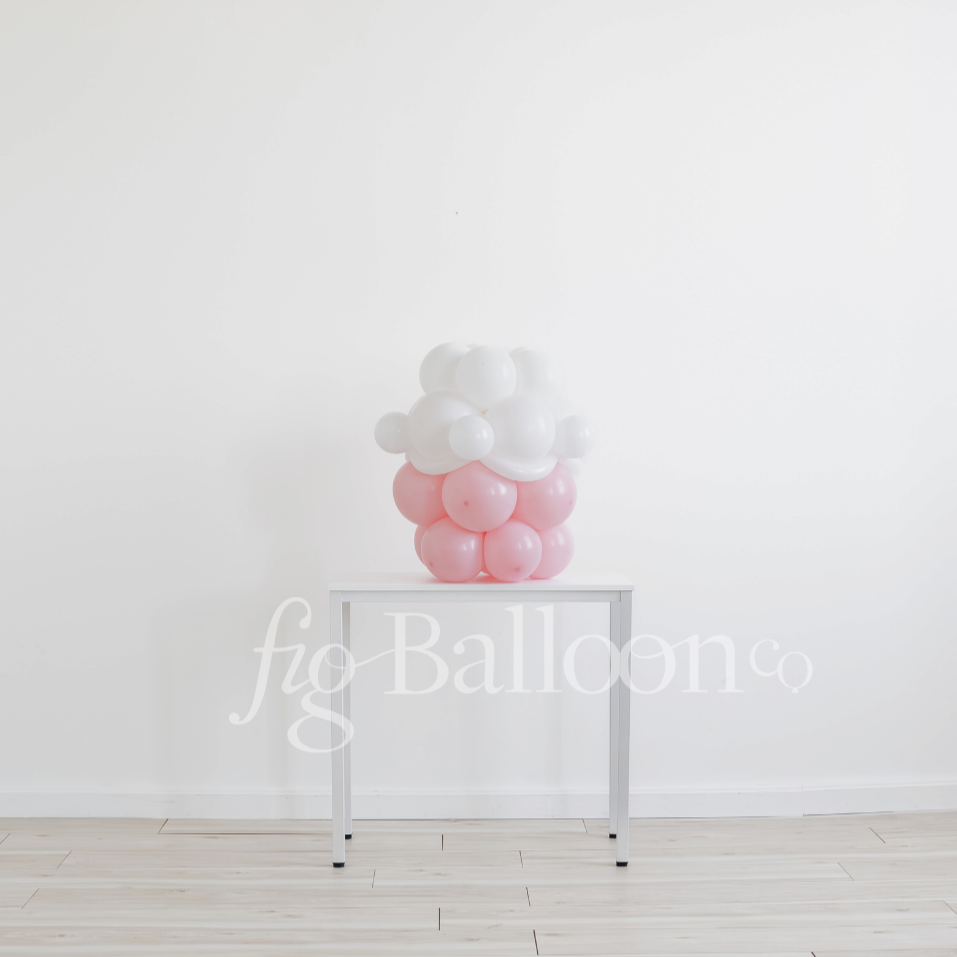 Decorative balloon display on a stand against a white wall with 'fig balloons' branding.