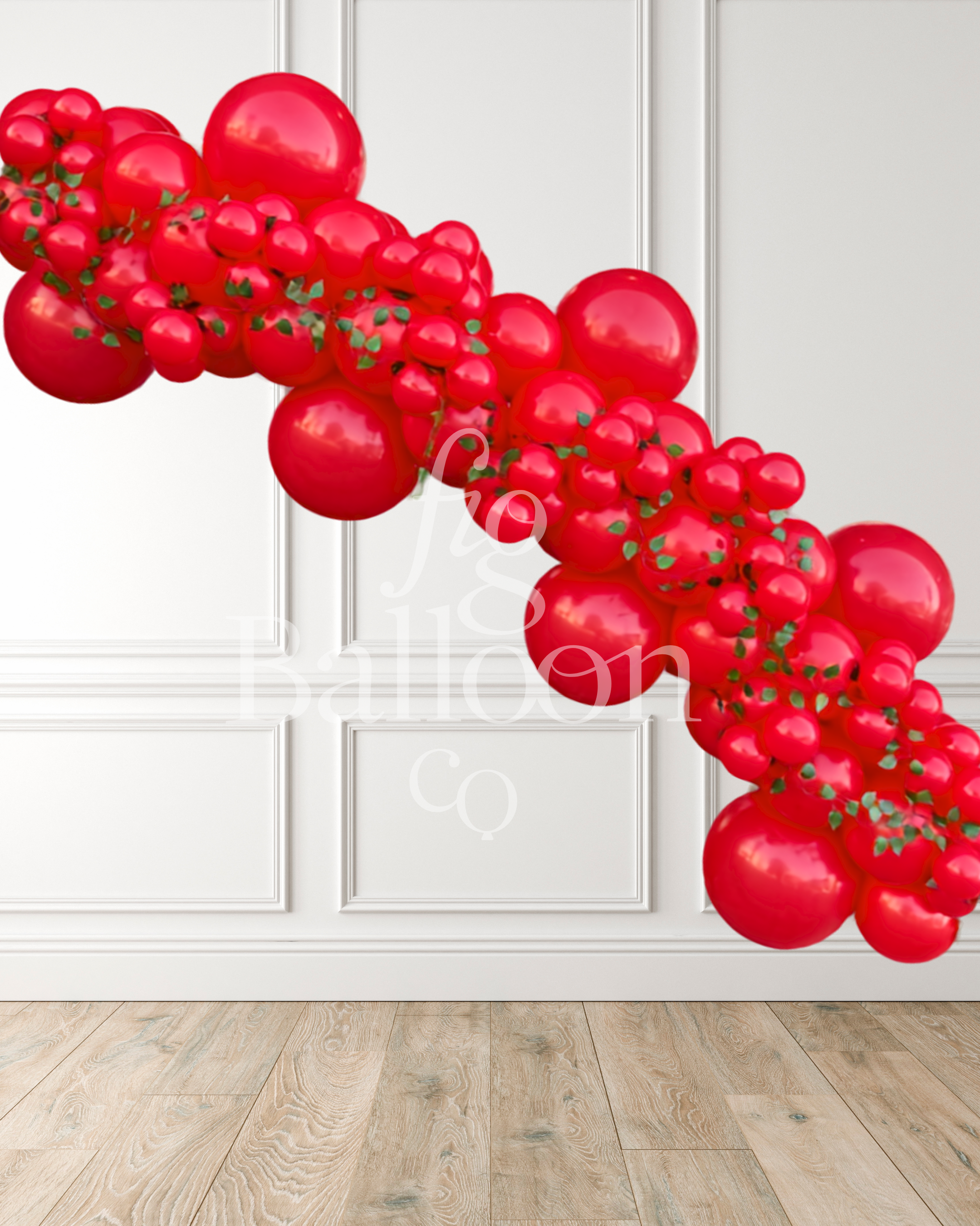 A red balloon garland made of glossy red latex balloons with small green leaf accents, displayed diagonally against a white paneled wall and light wood floor.