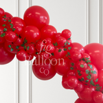 A red balloon garland arch decorated with green ivy vines, shown against a white paneled wall. A semi-transparent watermark reading 'fig balloon co' is overlaid across the center.